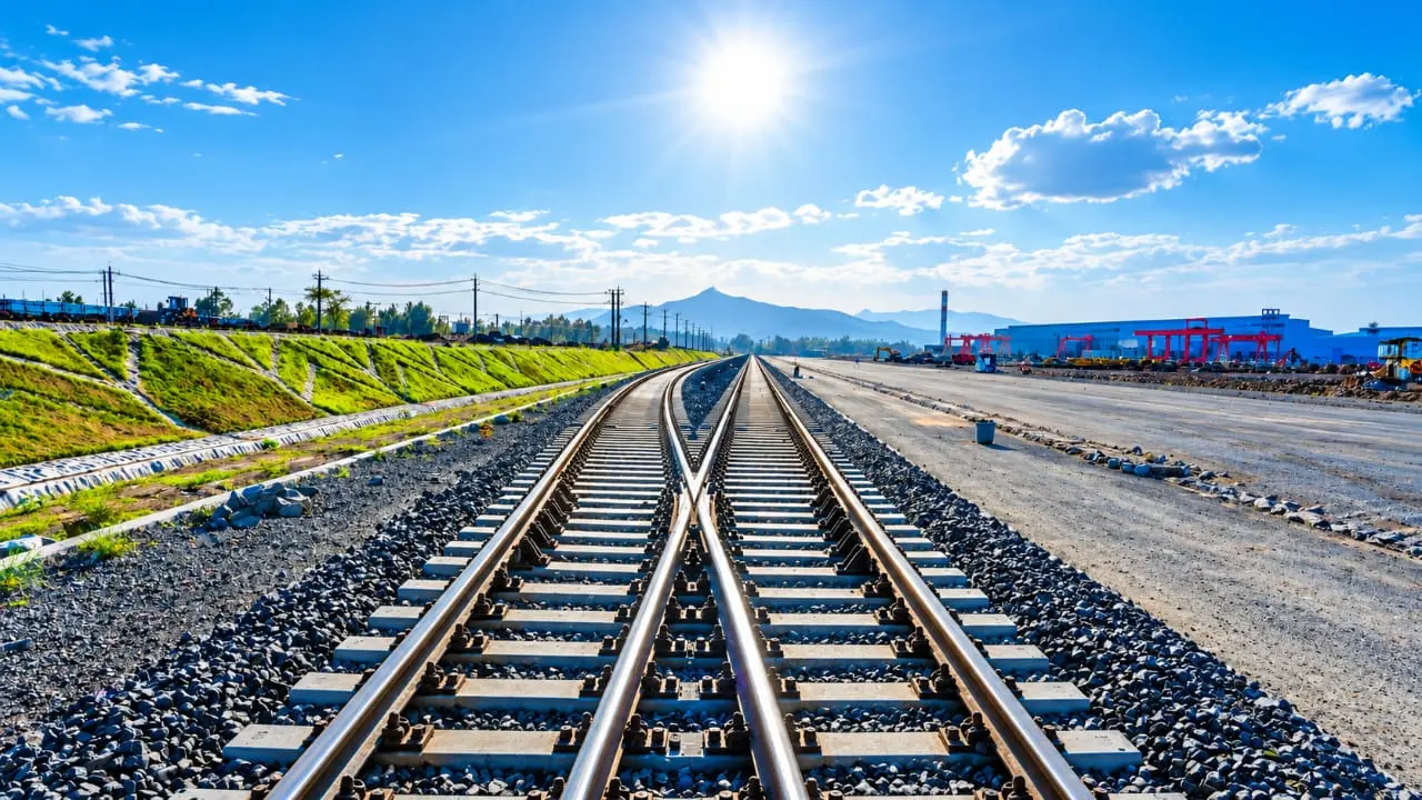 Two electrified tracks running together towards the horizon, overhead line masts on either side